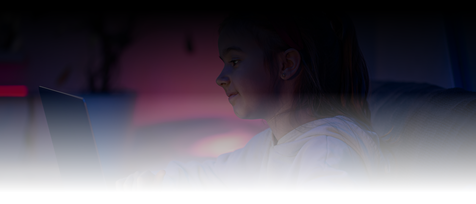 Child using a laptop in a dimly lit room